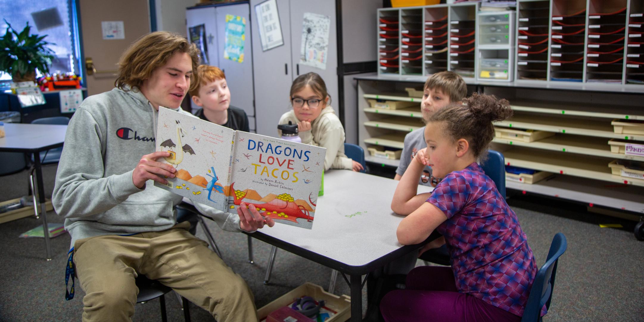 A high school student reads to younger students.