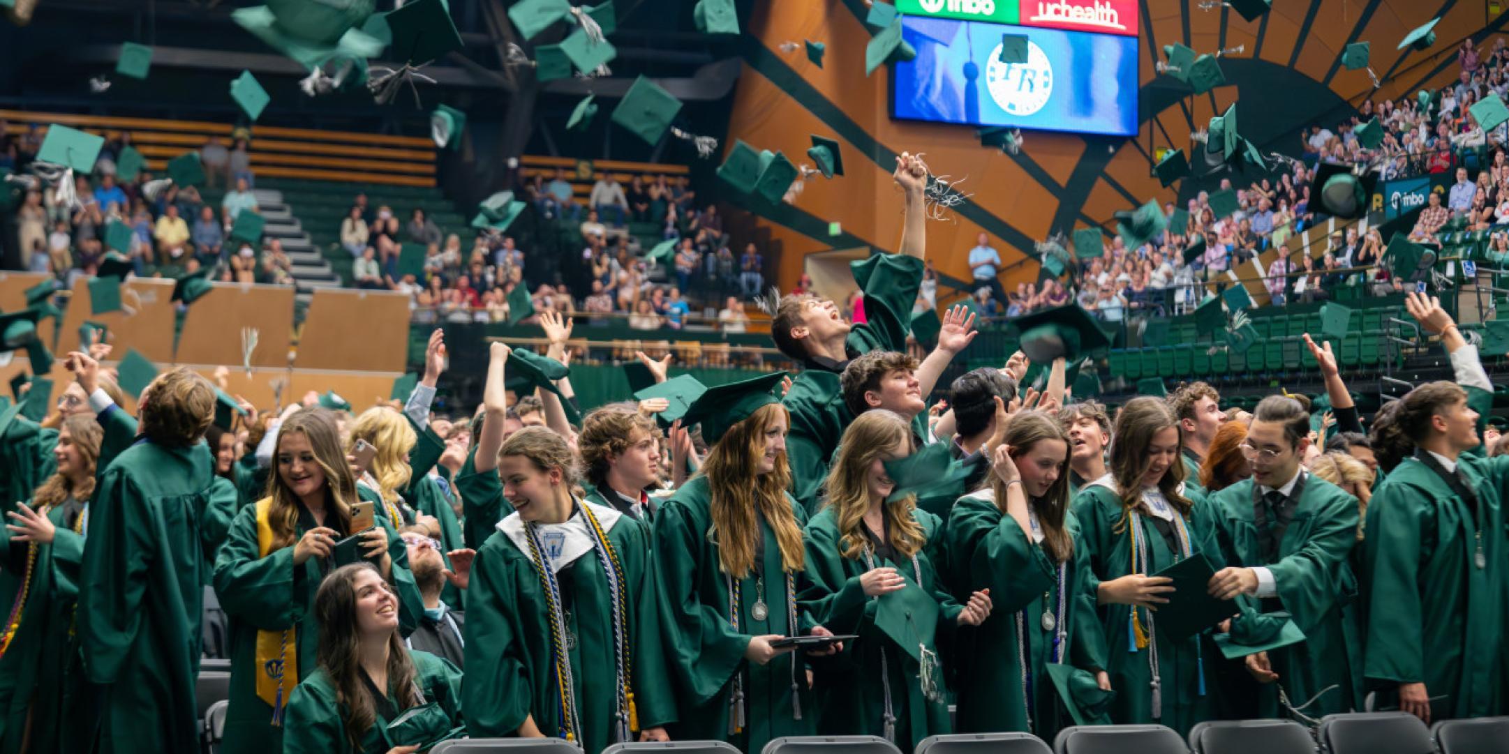 Fossil Ridge High School graduates throw caps in the air.